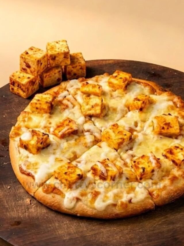 A freshly baked Loaded Paneer Pizza with golden crust and melted cheese on a dark rustic wooden serving board at Chetty's Corner Bangalore.